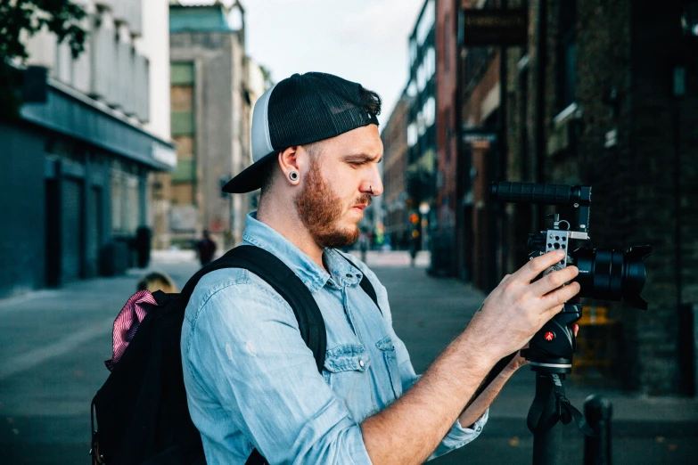 a man standing on a street corner while holding a camera