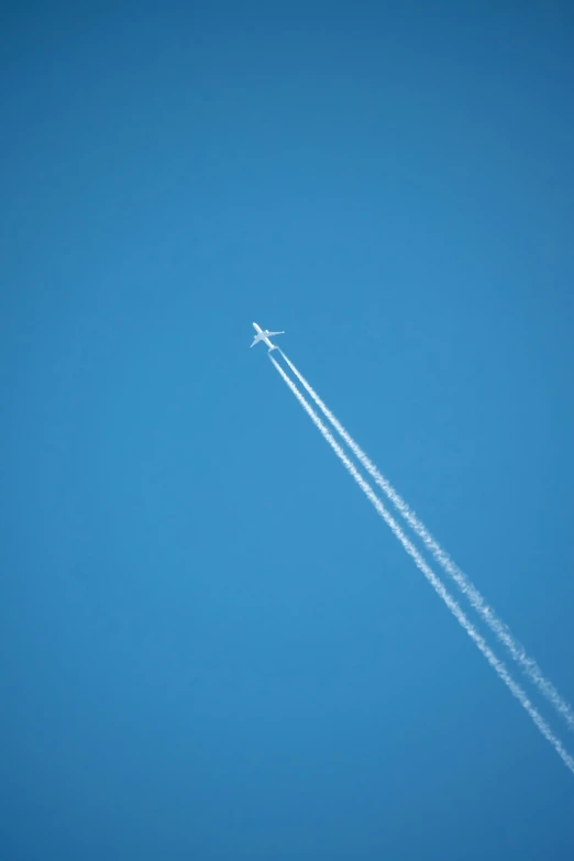 an airplane in a clear blue sky leaving a contrail