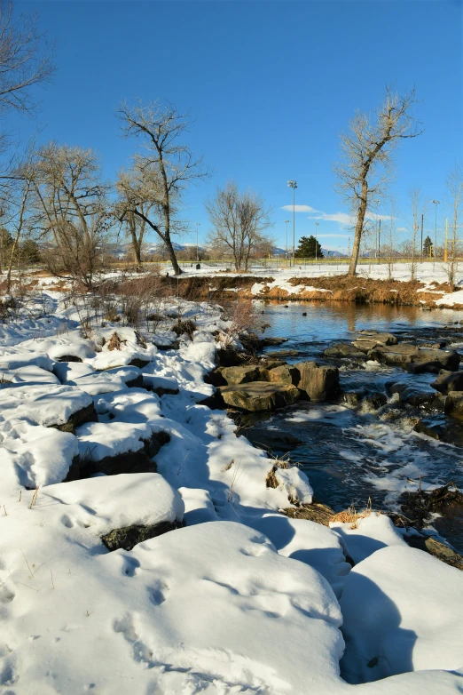 a snowy stream with a lone bench on the side