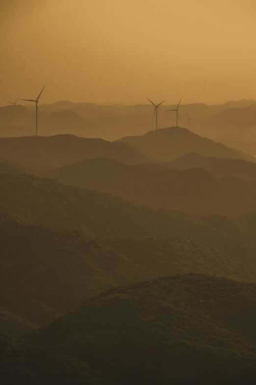 windmills in the distance surrounded by a hazy hillside