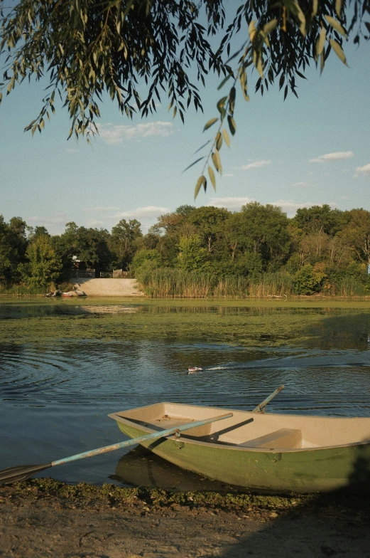 small boat sitting in the sand on a lake