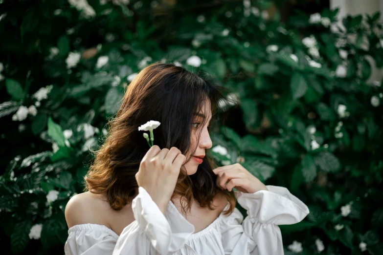 a young woman has her hair styled with a flower in one side