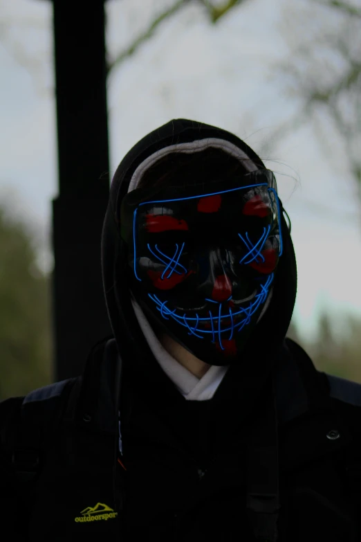 someone wearing a black glowing mask with blue light in front of them