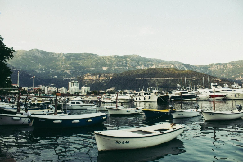 several boats are docked in an ocean by some mountains