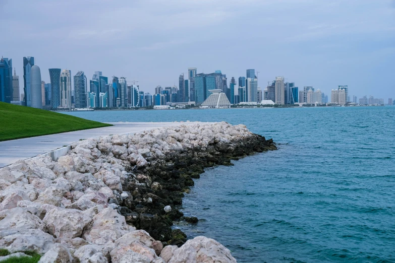 a stone and rock wall near the water in front of the city