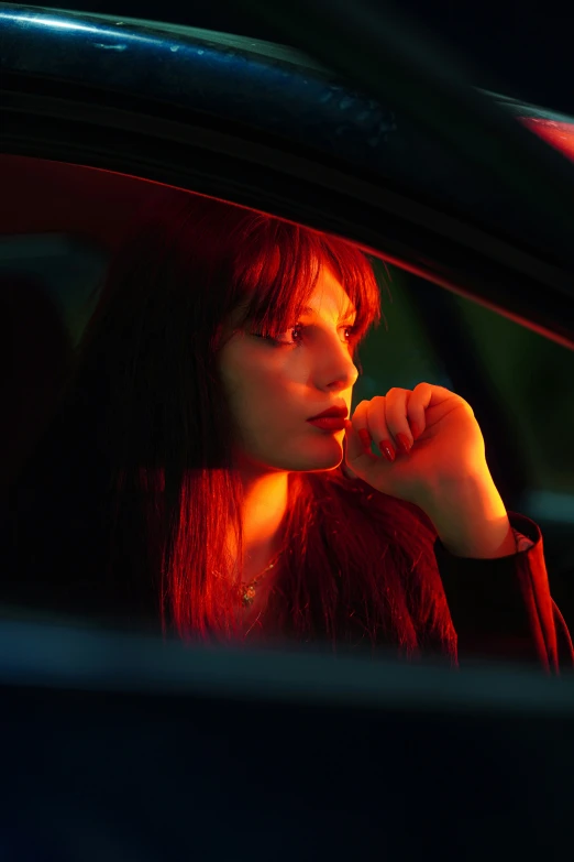 a beautiful young lady sitting in the car looking out the window