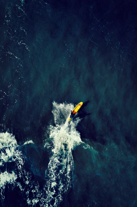 an aerial view of a paddle boarder flying over waves