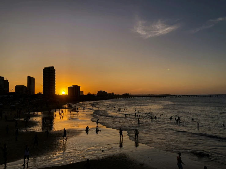 a group of people are at the beach with buildings in the background