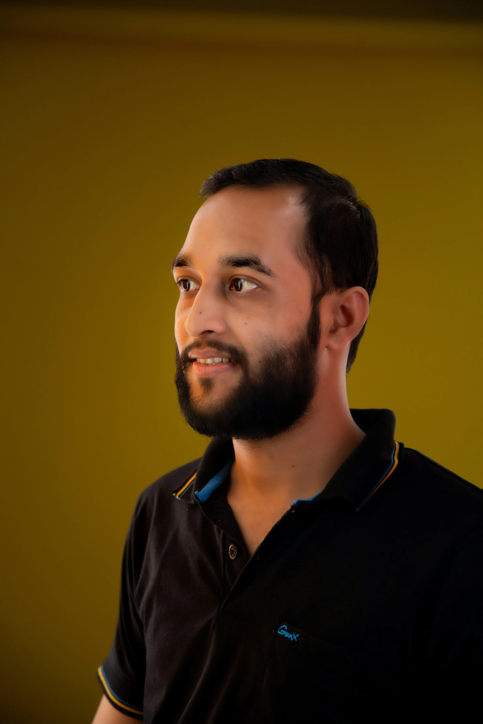 a man with a beard in front of a yellow wall