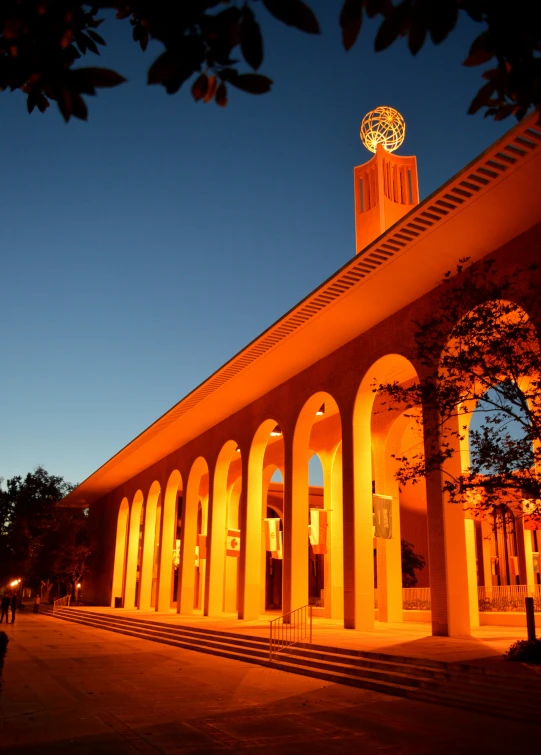 people walking down the walkway at a lighted building