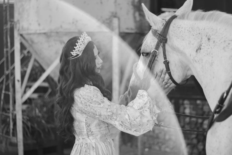 black and white po of a girl in dress petting a horse