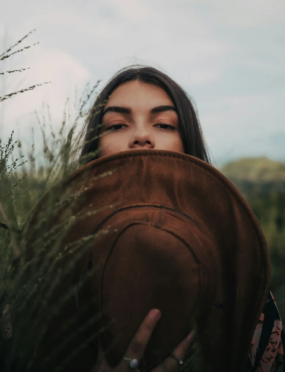 a woman hiding her face behind some grass