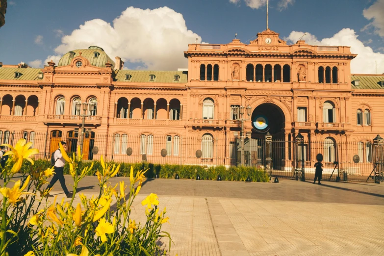 people walking near a large, ornate building with tall arches