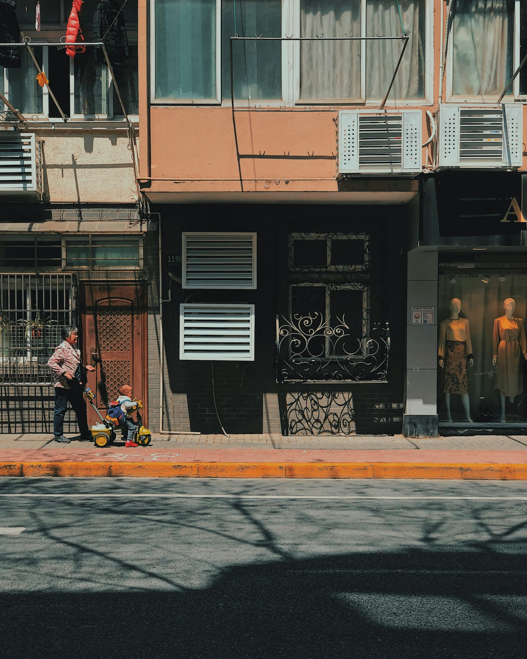 an older man walks past old fashion clothes in front of a red building