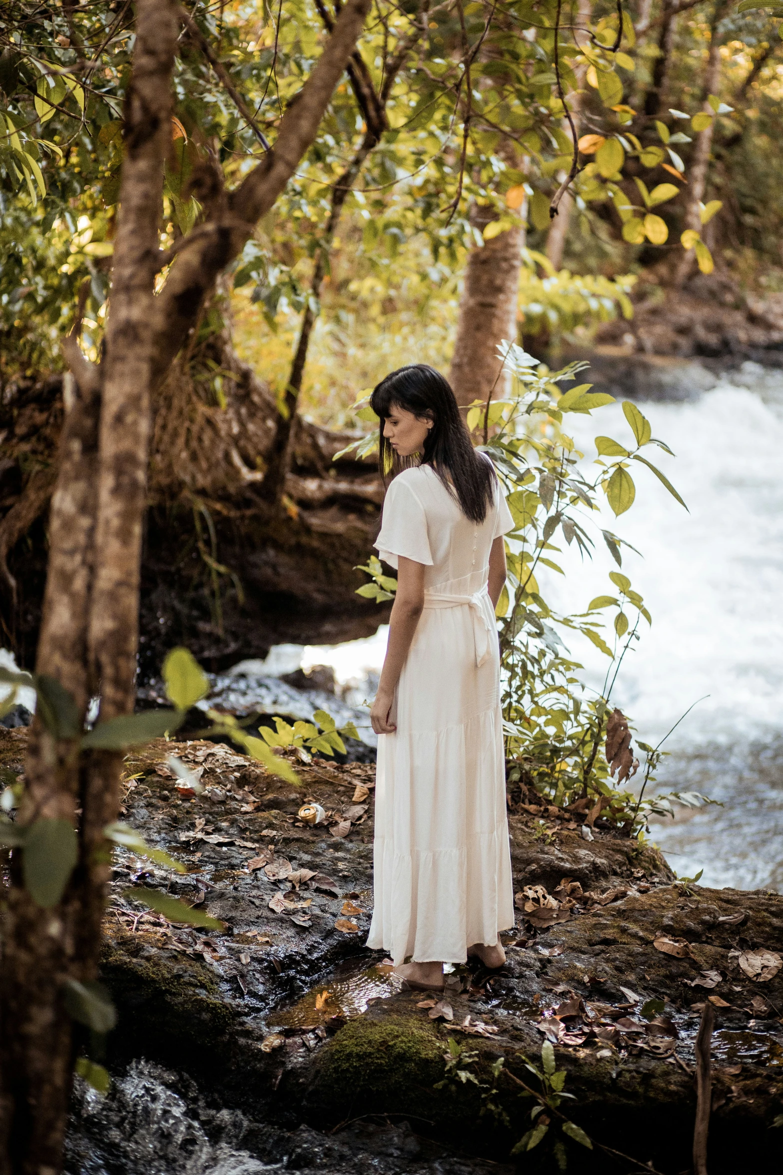 a woman in a white dress and hat looks at water