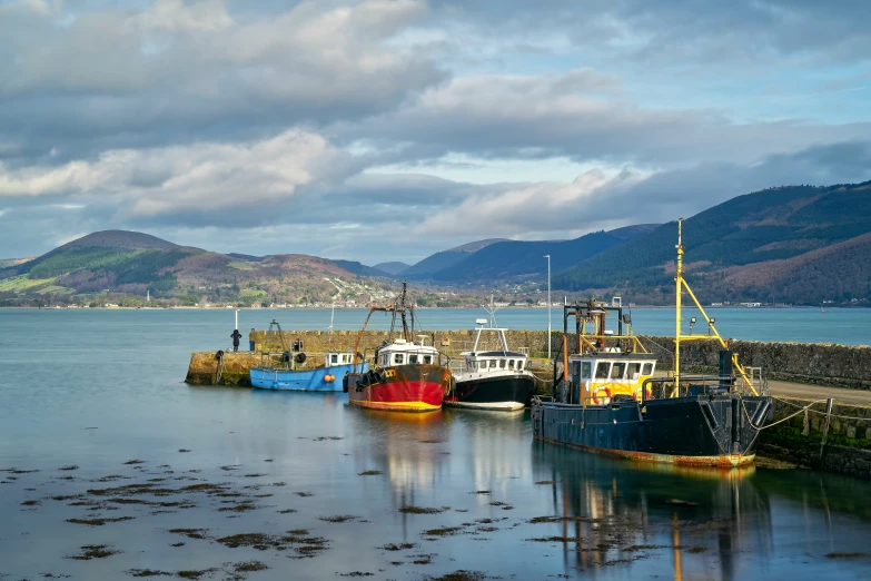 three boats are parked on the water beside a pier