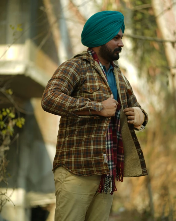 a man in a green turban and tan pants is standing