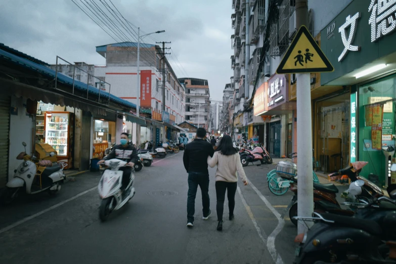 two people walking down the street near some motorbikes