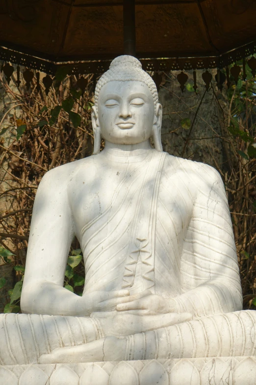 a buddha statue sits in a peaceful position on a stone pedestal