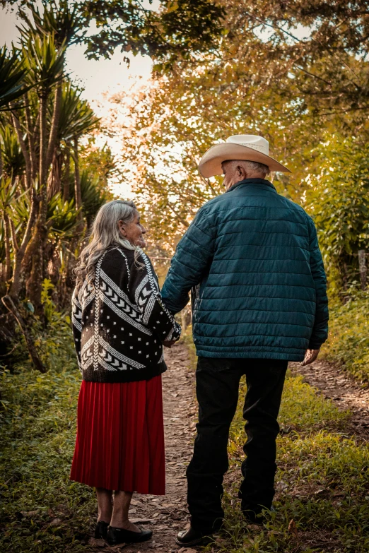 a man and woman stand holding hands on the path