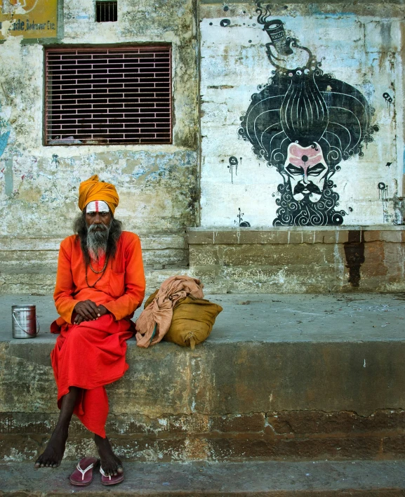 a man sitting on a wall outside in orange outfit