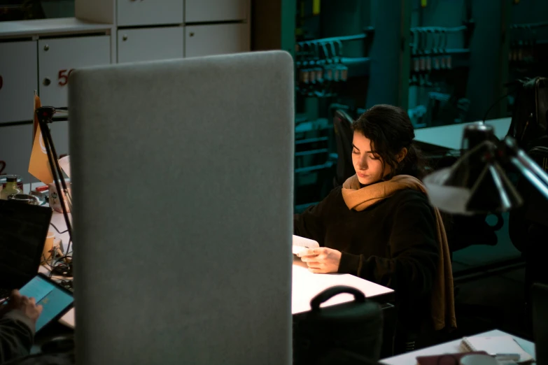 two women sit at a desk in front of a computer