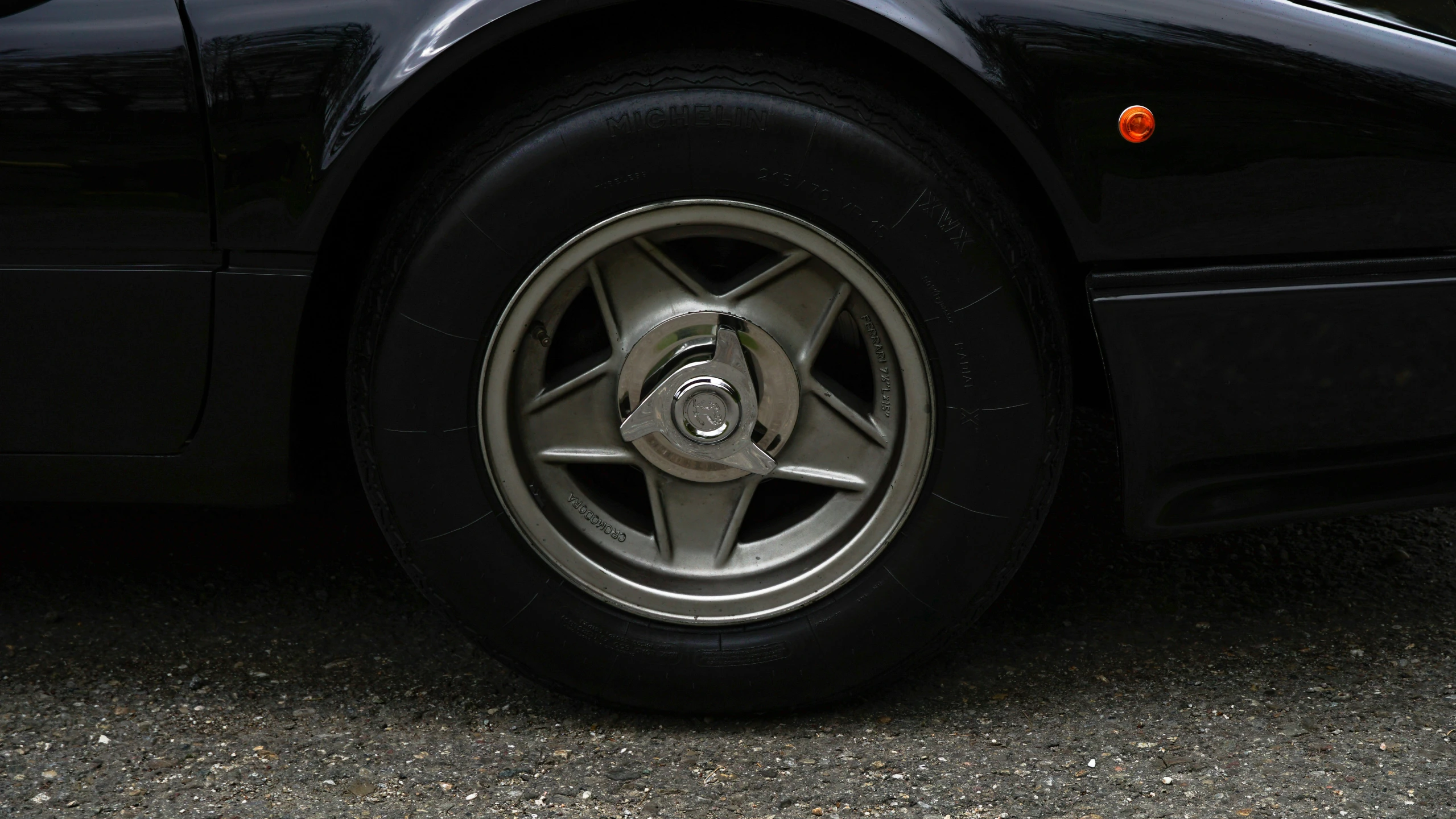 black car tire with wheel clamp and red light on