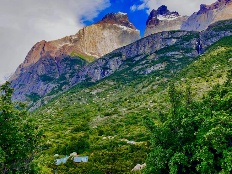 mountains towering above a lush green forest under a cloudy sky