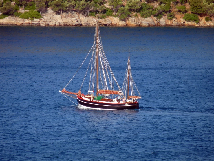 a sail boat out on the water in a blue sky