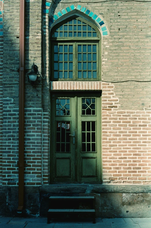 a light on a pole stands in front of a green door