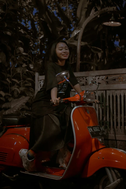 a woman is sitting on an orange scooter smiling