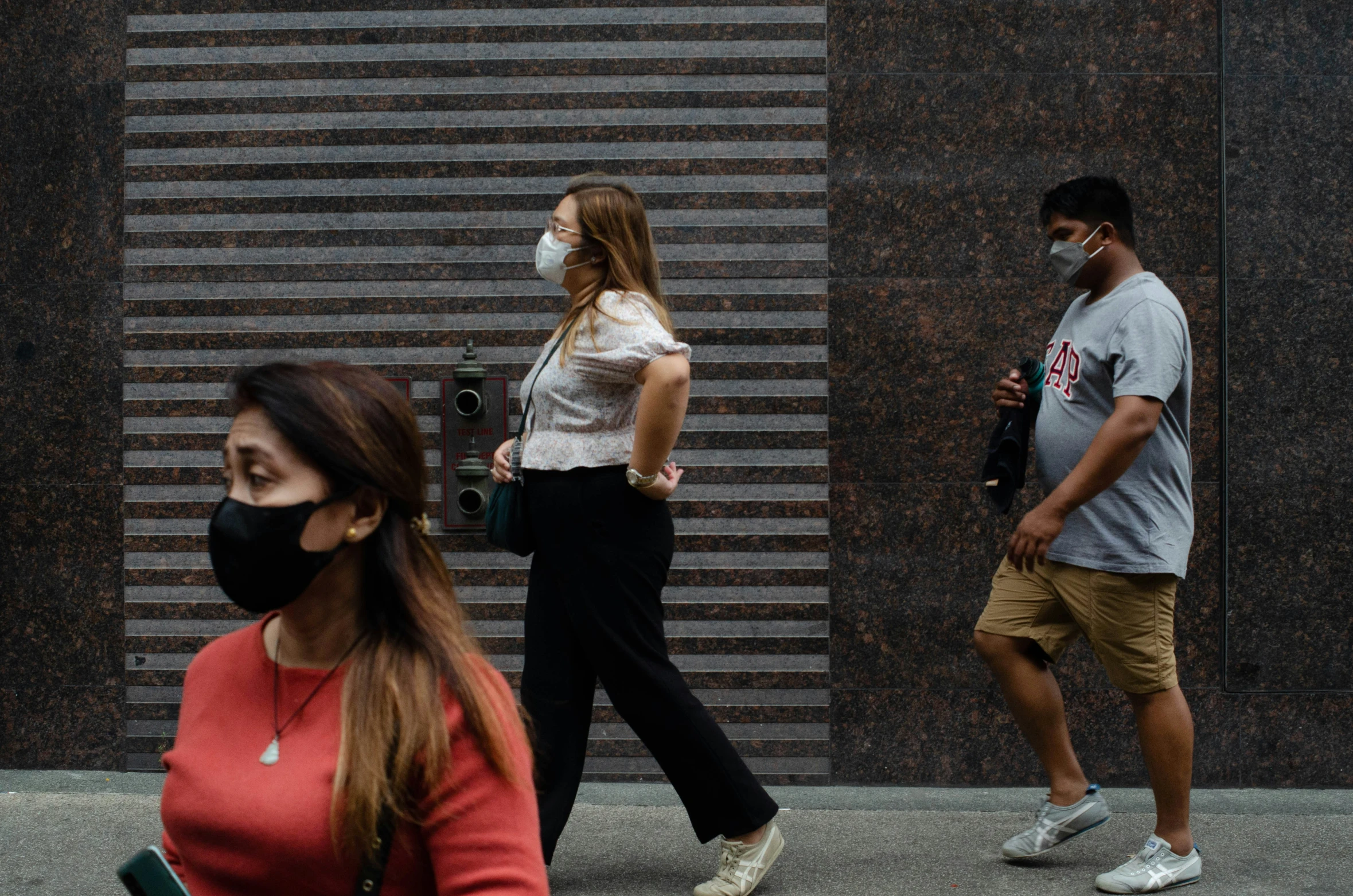 people walking on sidewalk wearing face masks in urban setting