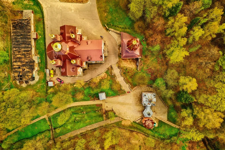 an aerial view shows the location where a large red house sits on a green valley surrounded by trees