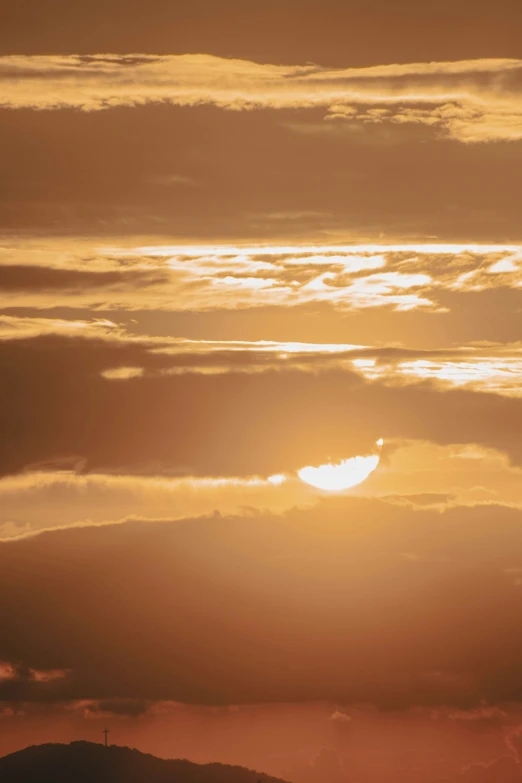 a plane is flying over some mountains with the sun setting