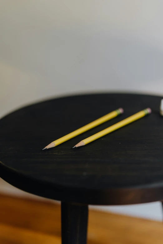two pencils and sharpener resting on top of a black table