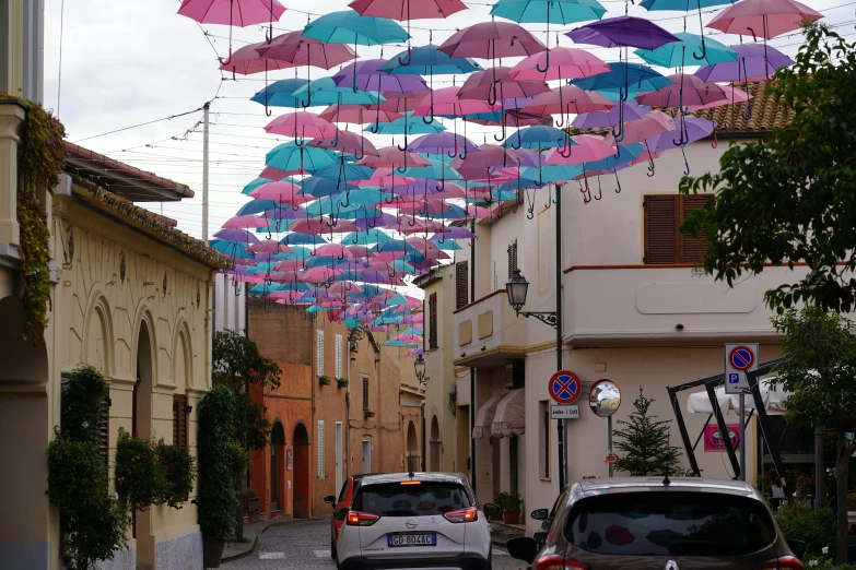 a street has multiple umbrellas hung above it