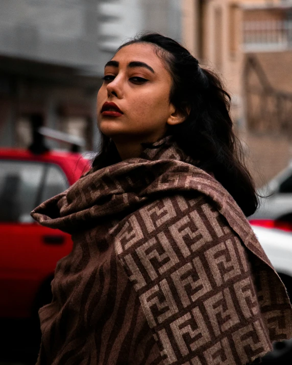 a woman standing on a city street under a blanket