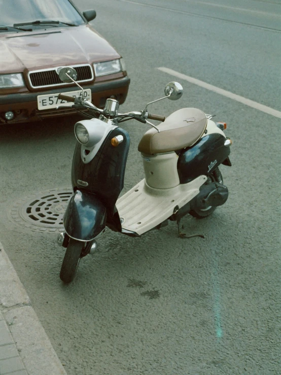 a moped parked near a road next to a car