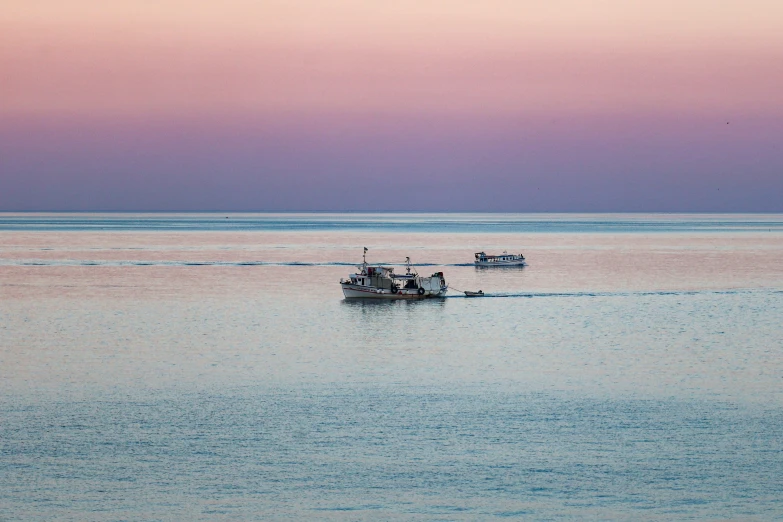 a small boat sailing through the water under a sunset sky