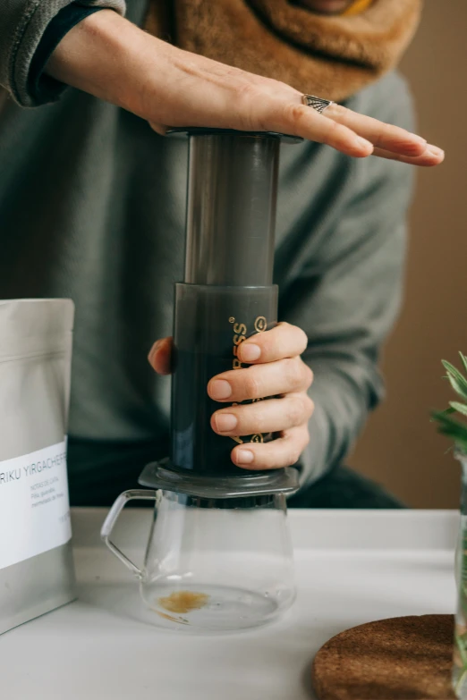 a hand holding onto a juicer on top of a table