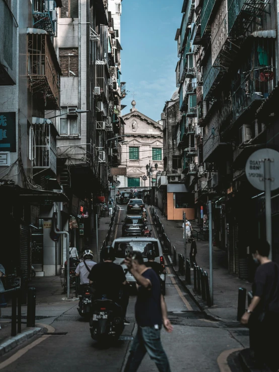 some cars are driving down the narrow city street