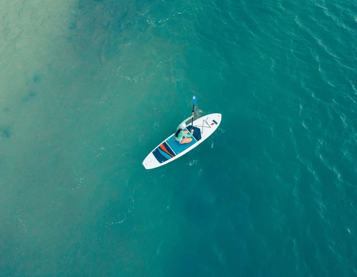 man in small boat floating in blue water