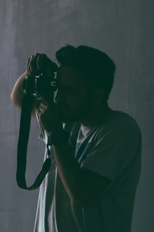 man holding up camera to take pograph in dark environment