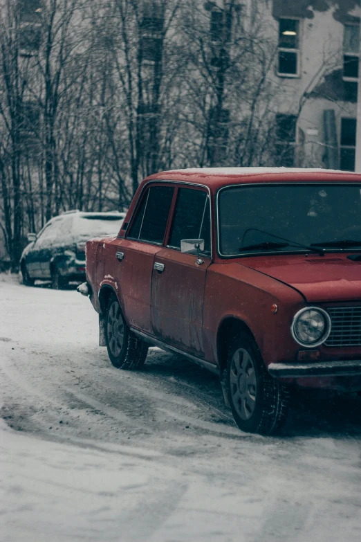 an old, red car sits on a snowy street