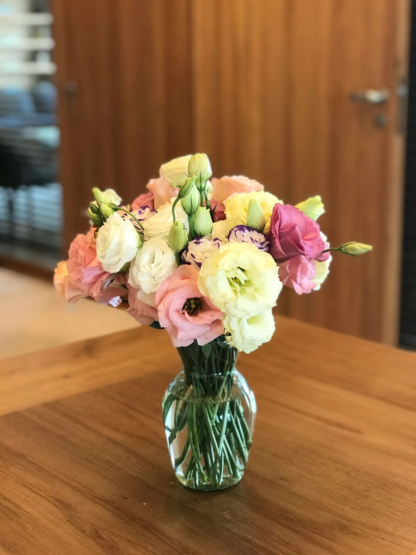 a bouquet of flowers sits in a glass vase on a wooden table