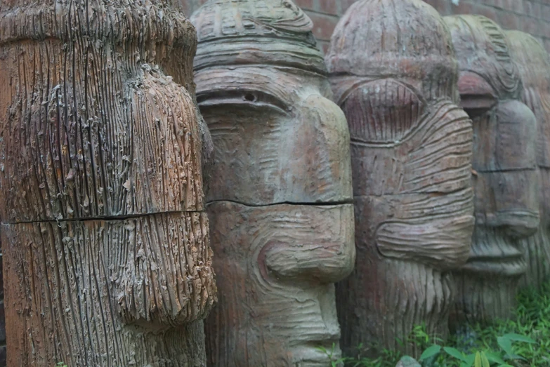 a row of wooden carved faces of people and woman
