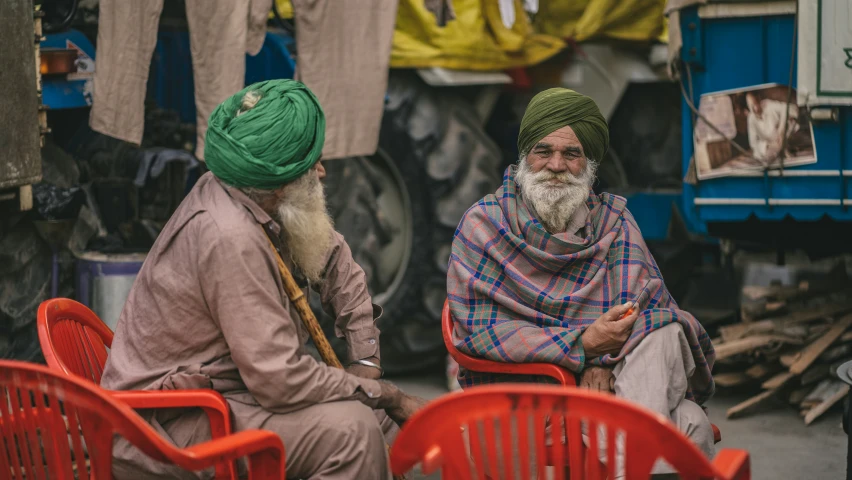 a couple of men sitting next to each other on red chairs