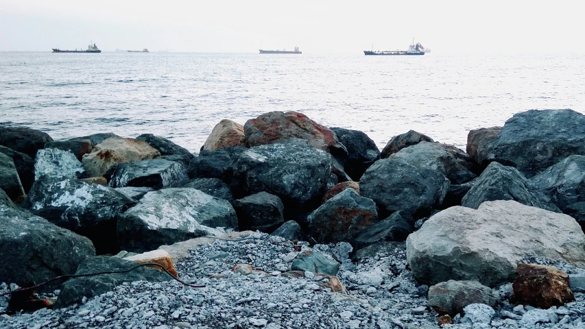 two boats sit in the distance off the coast