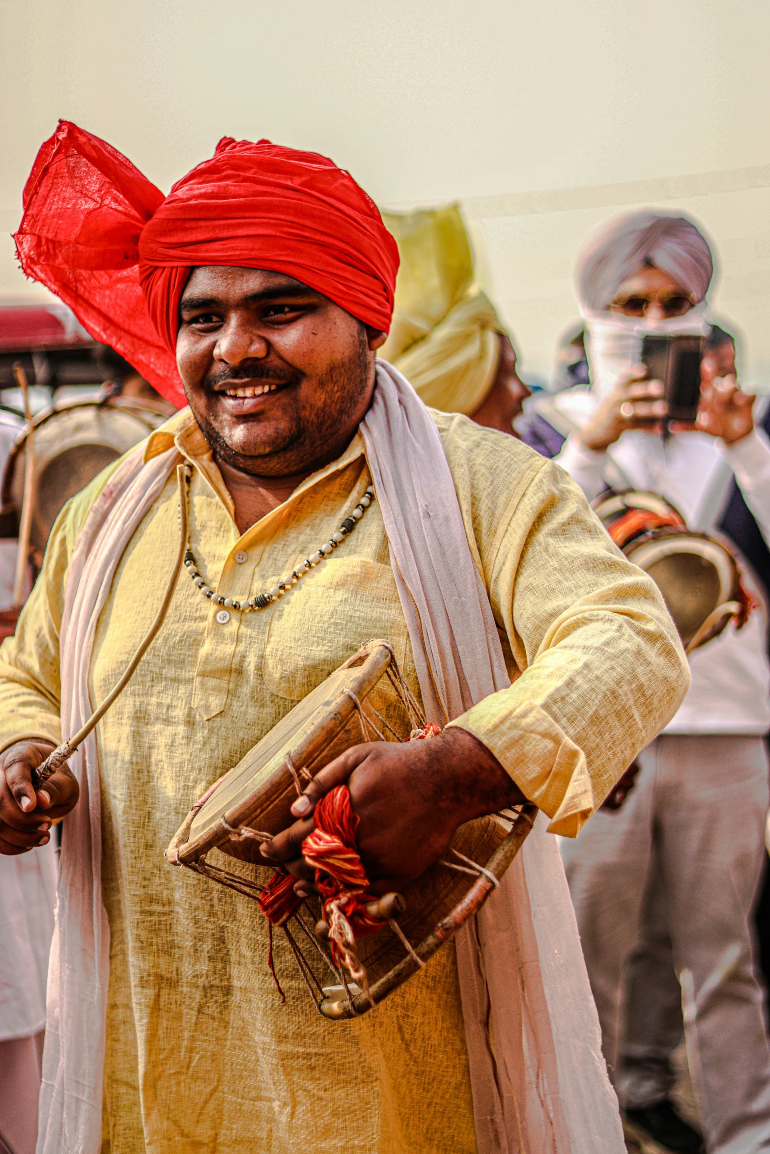 a man with a red turban on his head and holding an object