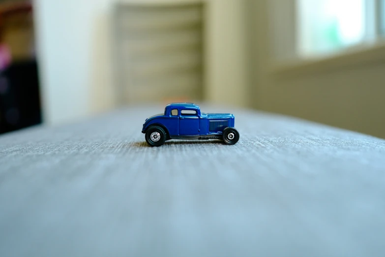 an antique blue toy car sits on the bed